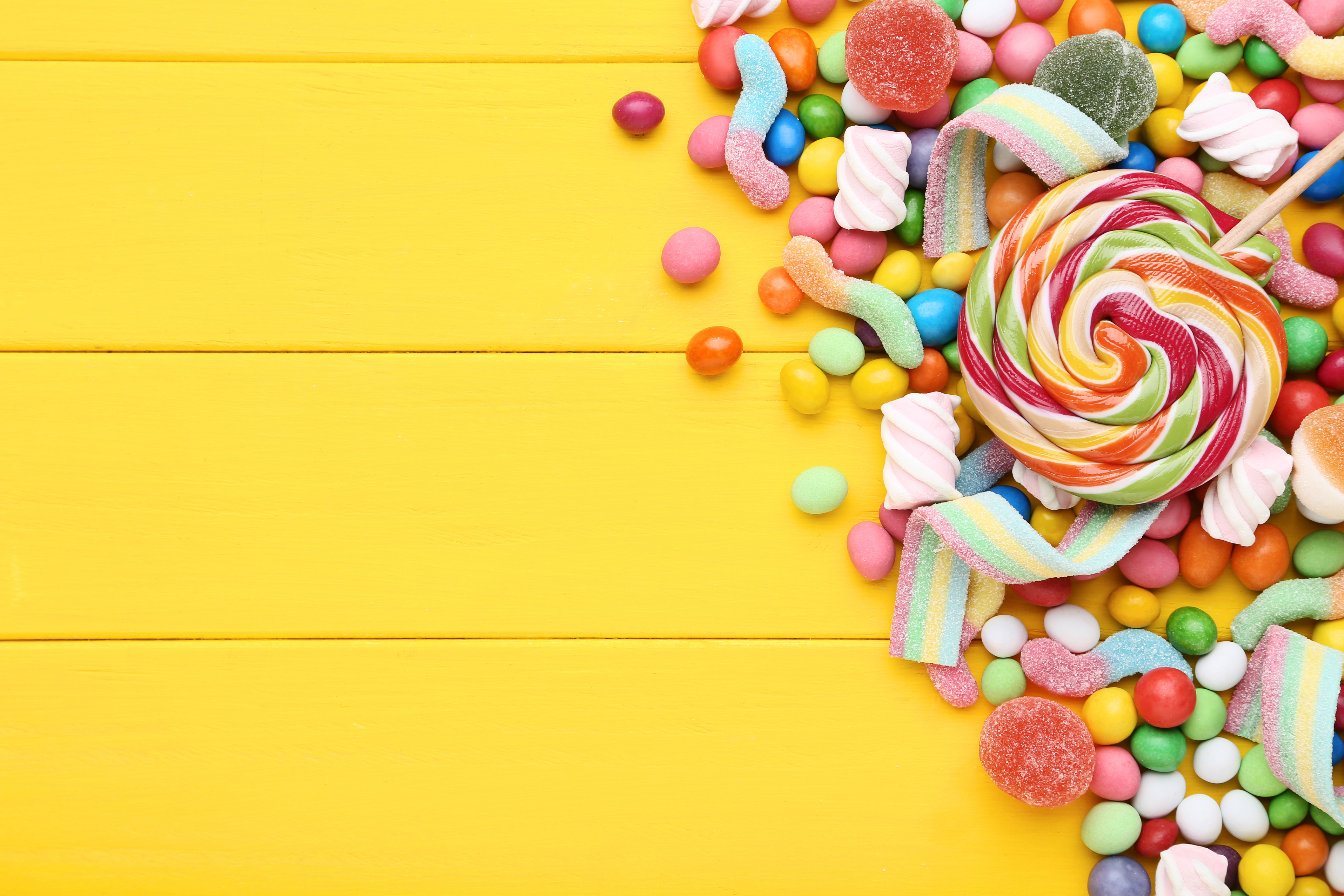 Sweet candies and lollipops on yellow wooden table